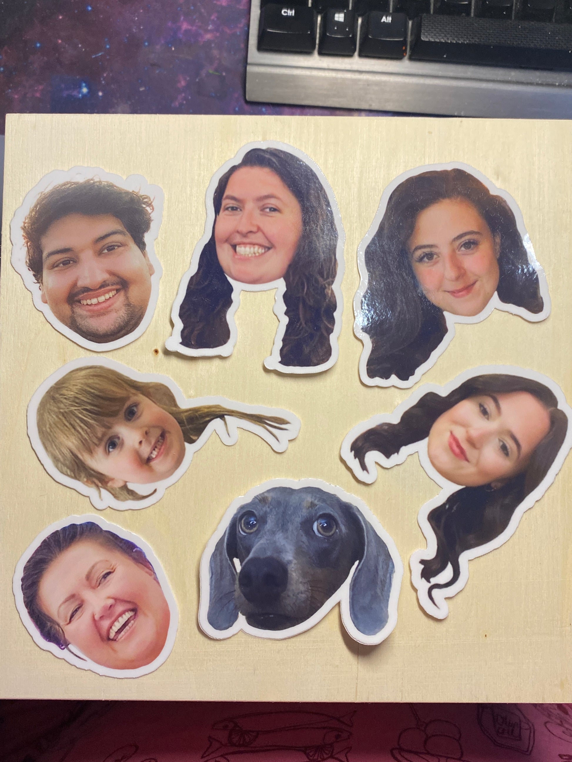 Stickers with cut-out faces arranged on a wooden surface